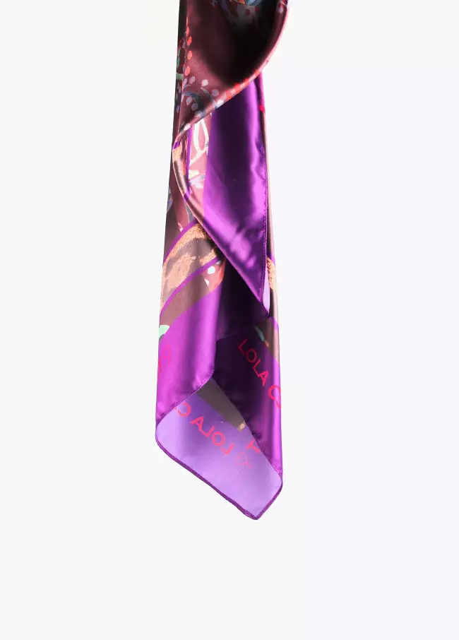 Pañuelo estampado tipo cachemire en tonos violetas con letras logo en el centro.